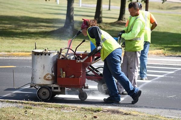 Employees using specialized road line painting equipment to paint lines on the road