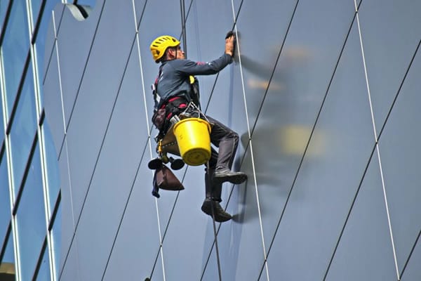 Window cleaner suspended on side of highrise building